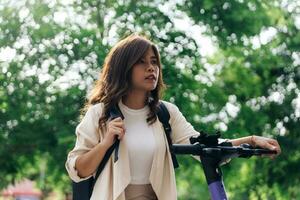 kant visie van jong vrouw met rugzak rijden elektrisch scooter in park foto