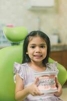 Aziatisch meisje in tandheelkundig stoel, met tand borstel. geneesmiddel, tandheelkunde en gezondheidszorg concept foto