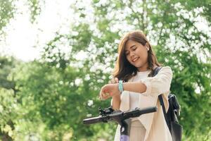 jong vrouw gebruik makend van SmartWatch terwijl rijden een fiets in de park. foto