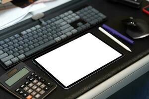 digitaal tablet blanco scherm Aan de bureau met toetsenbord rekenmachine pen en muis. foto
