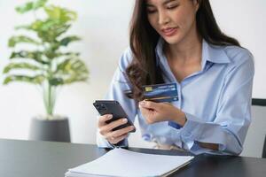 mooi Aziatisch Dames gebruik makend van credit kaarten voor boodschappen doen online met laptops en smartphones, online boodschappen doen portret concept. foto