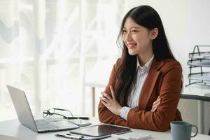 Aziatisch zakenvrouw glimlachen vol vertrouwen geslaagd ondernemer elegant professioneel bedrijf uitvoerend vervelend een pak staand in de kantoor met armen gekruist. foto