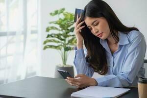 ongelukkig Aziatisch jong vrouw zittend Bij huis gebruik makend van mobiel telefoon hebben probleem boodschappen doen online met een credit kaart. gevoel angstig en verward door de fouten van internet bankieren. foto