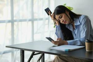 ongelukkig Aziatisch jong vrouw zittend Bij huis gebruik makend van mobiel telefoon hebben probleem boodschappen doen online met een credit kaart. gevoel angstig en verward door de fouten van internet bankieren. foto