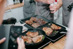 Koken steaks in een pan. Koken rundvlees Bij de culinaire meester klas. de handen van de chef in zwart handschoenen. foto