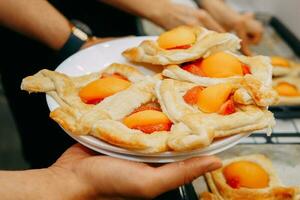 voorbereidingen treffen een toetje Bij een Koken meester klas. manden met perziken en aardbeien, huis Koken. detailopname. gebakjes, taarten met perziken van bladerdeeg gebakje. foto