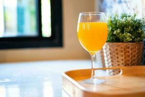 oranje sap in een wijn glas is geplaatst Aan de tafel in de keuken. foto