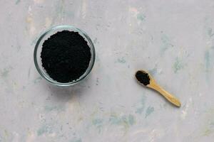 zwart geactiveerd houtskool poeder in kom en lepel foto