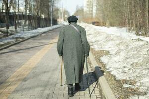 gepensioneerde wandelingen naar beneden weg. ouderen vrouw Aan straat. wandelen in park. foto