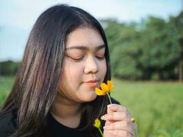 portret van tuinman jong vrouw Aziatisch mollig schattig mooi een persoon op zoek hand- Holding zorgzaam voor planten bladeren tuin park schoonheid bloemen avond zonlicht vers glimlachen gelukkig kom tot rust zomer dag foto