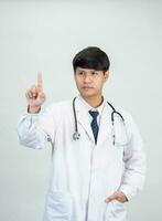 Aziatisch Mens leerling wetenschapper of dokter een persoon, vervelend een wit gewaad, staan, op zoek en lachend, wit achtergrond met een stethoscoop ausculteren de hart in de omgeving van zijn nek. foto