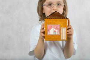 jongen van vijf jaren is houden handgemaakt karton papier huis. foto
