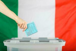 vrouw hand- houdt stemming over- stemming doos. Italiaans vlag in de achtergrond. foto