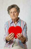 oud vrouw houdt een hart in haar handen foto