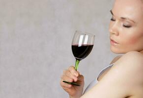 jong dame houdt een glas van rood wijn in haar hand- foto