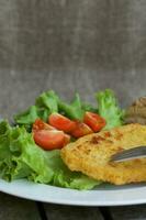 kip schnitzel met kers tomaten en groen salade bladeren. foto