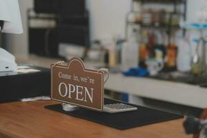 open. barista, serveerster vrouw vervelend bescherming gezicht masker draaien Open teken bord Aan glas deur in modern cafe koffie winkel, cafe restaurant, kleinhandel op te slaan, klein bedrijf baasje, voedsel en drinken concept foto