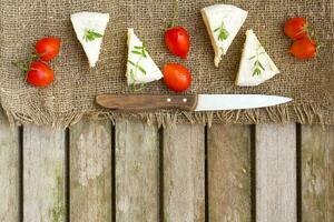 voedsel ingrediënten Frans kaas en kers tomaten Aan een houten oppervlakte foto