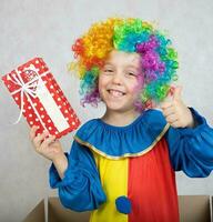 jongen van vijf jaren gekleed in de kostuum van een clown met een geschenk. foto