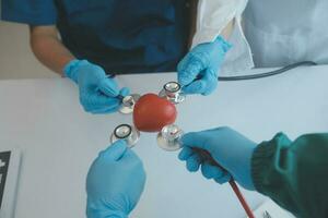 multiraciaal medisch team hebben een vergadering met artsen in wit laboratorium jassen en chirurgisch scrubs gezeten Bij een tafel bespreken een patiënten records foto