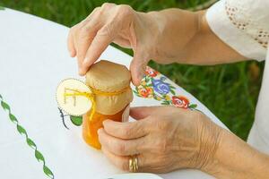 een oud vrouw is opening een glas van marmelade. foto