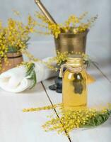 mimosa bloemen massage olie in glas fles. foto