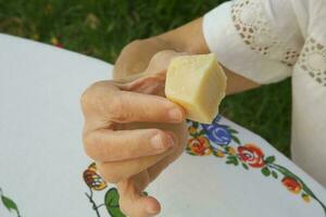 een stuk van Parmezaanse kaas kaas in de hand- van een oud vrouw foto