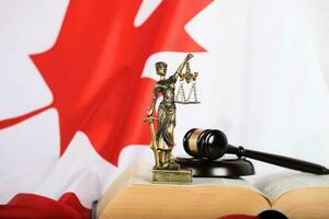 standbeeld van themis en van de rechter hamer Aan een boek. vlag van Canada in de achtergrond. foto