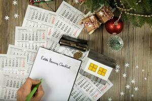 vel van papier -landgoed planning checklist en klein papier huis met munten Aan de nieuw jaar achtergrond. foto