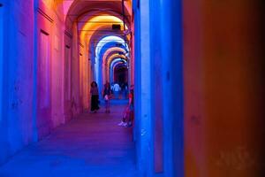 Bologna, Italië- juni 23, 2023-mensen wandeling Bij nacht onder de arcades leidend naar de heiligdom van san luca verlichte voor de eerste editie van de bologna arcades festival. foto