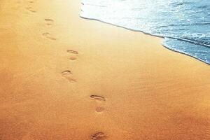 wandelen op het strand, voetstappen achterlatend in het zand. foto