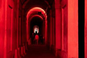 Bologna, Italië- juni 23, 2023-mensen wandeling Bij nacht onder de arcades leidend naar de heiligdom van san luca verlichte voor de eerste editie van de bologna arcades festival. foto