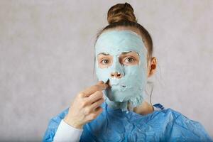 jong dame heeft een gezicht masker zittend in cosmetologisch fauteuil foto