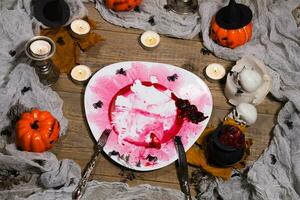 vuil rood bloederig bord met zilver bestek Aan halloween tafel. , bord foto