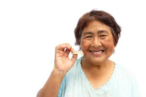 oude oude Thaise vrouw glimlacht en houdt gebit en leeg gebied aan de linkerkant foto