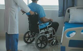 revalidatie van gehandicapt mensen concept. jong fysiotherapeut helpen senior mannetje geduldig in rolstoel oefening Bij huis. gehandicapten ouderen Mens opleiding met halters foto