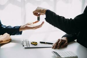 hand- Holding auto sleutels en auto verhuur concept een detailopname visie van de tussenpersoon, geven de klant de auto sleutels na ondertekening de huren, verhuur het formulier en auto naam. foto