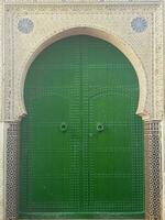 een groen houten deur omringd door ornamenten in de oude stad van tetouan, Marokko foto