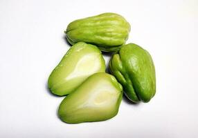 geheel chayote en chayote besnoeiing in voor de helft, wit achtergrond. foto