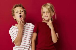 jongen en meisje glimlachen en poseren in gewoontjes kleren tegen Aan gekleurde achtergrond foto