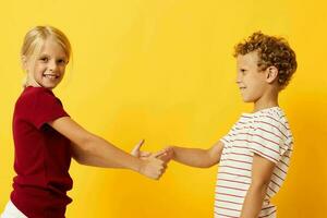 afbeelding van positief jongen en meisje staand kant door kant poseren kinderjaren emoties geel achtergrond foto