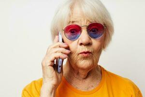 foto van gepensioneerd oud dame in gewoontjes t-shirt zonnebril pratend Aan de telefoon detailopname emoties