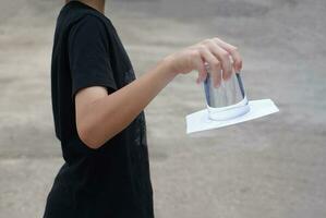 detailopname hand- houden en beurt een glas van water over- omlaag. gedekt de glas met papier. concept, wetenschap experiment over lucht en vloeistof druk. gemakkelijk wetenschap onderwerpen werkzaamheid, onderwijs. foto