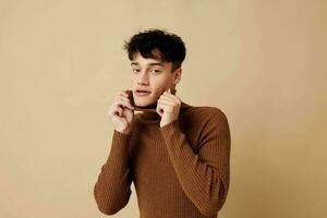 een jong Mens poseren in bruin trui zelf vertrouwen mode licht achtergrond ongewijzigd foto