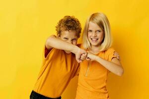 twee blij kinderen in geel t-shirts staand kant door kant kinderjaren emoties geel achtergrond foto