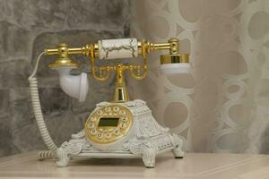 wit retro telefoon met een goud ontvanger Aan een muur achtergrond. de stamvader van de smartphone. foto