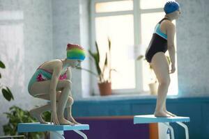 meisjes in een zwempak en een zwemmen pet met bril in de sport- zwembad. foto