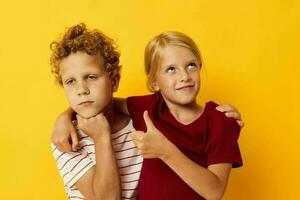 jongen en meisje knuffelen mode kinderjaren vermaak geel achtergrond foto