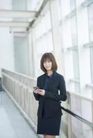 aantrekkelijke Aziatische zakenvrouw gebruiken op smartphone buiten kantoor foto