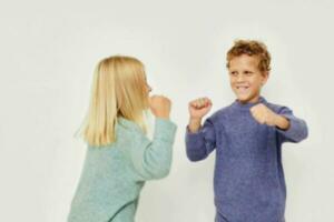 schattig elegant kinderen in veelkleurig truien poseren voor pret licht achtergrond foto